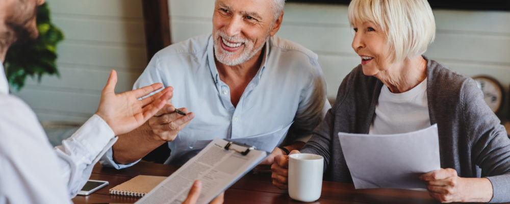 Happy aged couple consulting with insurance agent at home